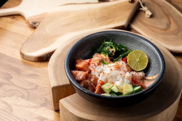 Çiğ somon kabı, beyaz pirinç, chuka ve salatalık ahşap kırsal masada. 