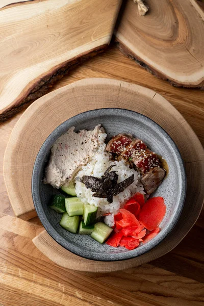 Tuna poke bowl with white rice, ginger and cucumber on wooden rustic table