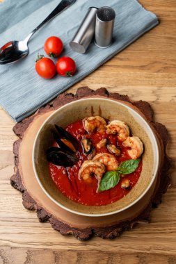 Sıcak ve baharatlı domates çorbası. Kral karidesleri, istiridye ve sarımsak. Tahta kırsal masa, üst manzara.