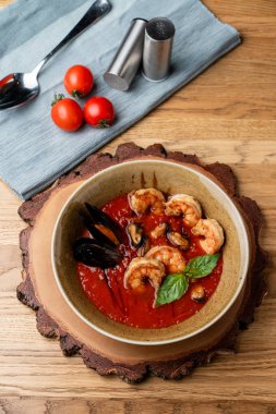 Sıcak ve baharatlı domates çorbası. Kral karidesleri, istiridye ve sarımsak. Tahta kırsal masa, üst manzara.