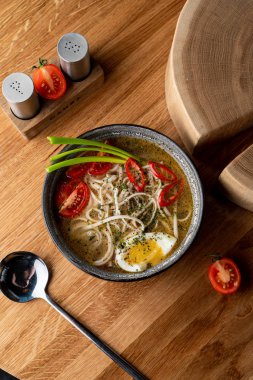 Tavuklu şehriye çorbası, haşlanmış yumurta, domates ve ahşap masada kırmızı biber.