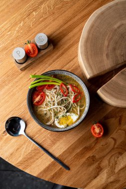 Tavuklu şehriye çorbası, haşlanmış yumurta, domates ve ahşap masada kırmızı biber.