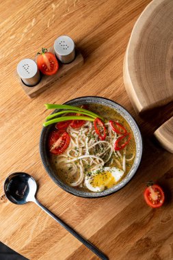 Tavuklu şehriye çorbası, haşlanmış yumurta, domates ve ahşap masada kırmızı biber.