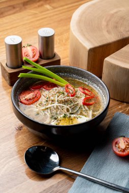 Haşlanmış yumurta, domates ve ahşap masada kırmızı biber ile sıcak tavuk çorbası.