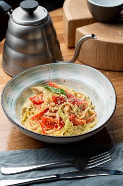 İtalyan makarnası tavuk göğsü, kremalı sos ve peynir bir İtalyan restoranında ahşap masada.