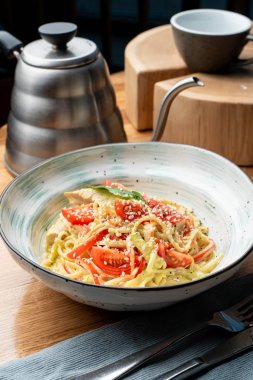 İtalyan makarnası tavuk göğsü, kremalı sos ve peynir bir İtalyan restoranında ahşap masada.