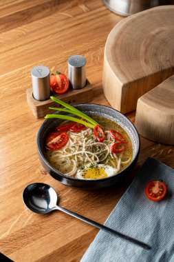 Haşlanmış yumurta, domates ve ahşap masada kırmızı biber ile sıcak tavuk çorbası.