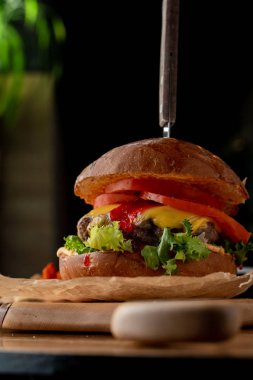 Çedar peynirli sulu sığır burger ve siyah arka planda patates kızartması.