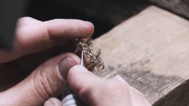 Production of rings. Jeweler working with with a blank of golden ring, grinding and polishing it with a special tool. Detailed shot with hands close up