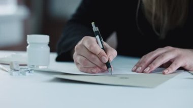 Young woman, a jewelry designer is drawing a sketch for a new ring at a jewelry production