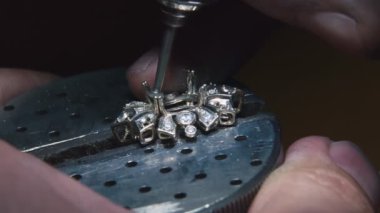 Production of rings. Jeweler working with with a blank of golden ring, grinding and polishing it with a special tool. Detailed shot with hands close up