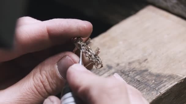 Production of rings. Jeweler working with with a blank of golden ring, grinding and polishing it with a special tool. Detailed shot with hands close up — ストック動画