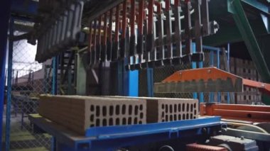 Gri tuğlalar tam otomatik fabrikanın üretim hattında ilerliyor.