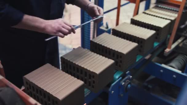 Vrouw in een beschermend uniform meet bakstenen om bederf in de productie op baksteenfabriek te voorkomen — Stockvideo