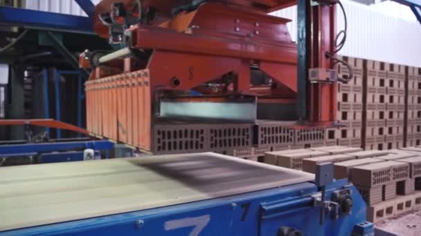 Braço robótico coloca tijolos cinzentos em uma linha em uma fábrica de tijolos — Vídeo de Stock