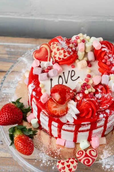 Close up of valentines day cake with strawberry, marshmallow and  heart shaped decorations on the kitchen table — Stock Photo, Image