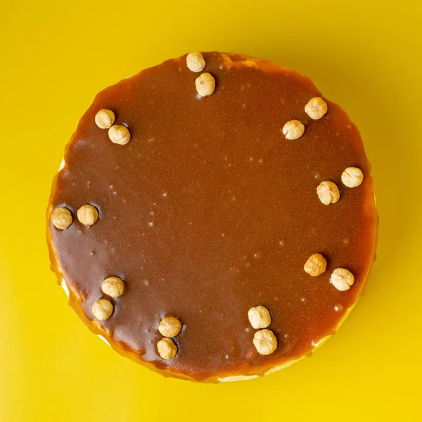 Gâteau aux noisettes et fromage à la crème avec caramel salé comme décoration sur fond jaune vif, directement au-dessus de la vue — Photo