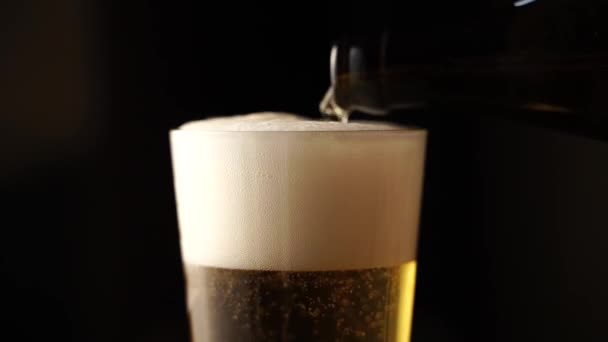 Выливание светлого золотого пива в стекло с пеной и пузырьками — стоковое видео