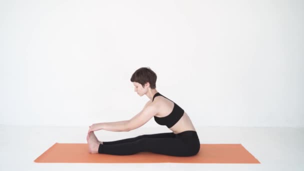 Young woman practicing yoga paschimottanasana and purvottanasana in white studio — Stock Video