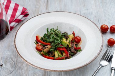 Ilık, roka, avokado ve kızarmış bira şeritli yemek salatası.