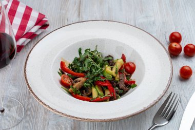 Ilık, roka, avokado ve kızarmış bira şeritli yemek salatası.