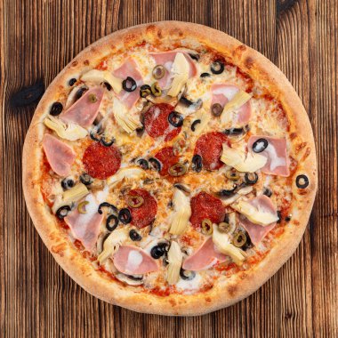 İtalyan restoranındaki ahşap masada enginarlı ve biberli pizza.