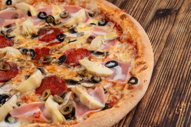 İtalyan restoranındaki ahşap masada enginarlı ve biberli pizza.