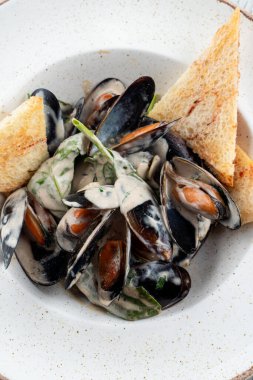 Krem soslu midye ve beyaz ahşap bir masada taze ıspanak.