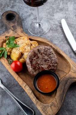 Biftek ve fırında patates rendelenmiş parmesan peyniri ve ahşap kesim tahtasının üzerinde hindistan cevizi.