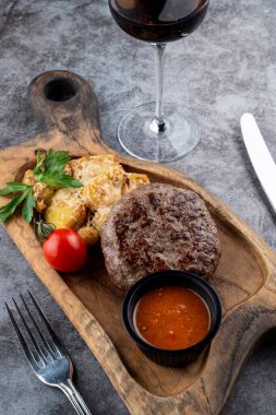 Biftek ve fırında patates rendelenmiş parmesan peyniri ve ahşap kesim tahtasının üzerinde hindistan cevizi.