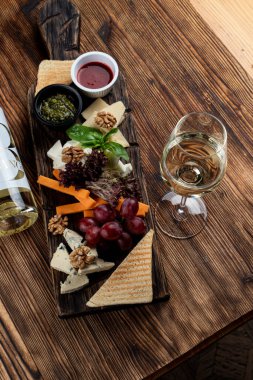 Grissini, peynir, dilimlenmiş et ve tahta üzerinde fındık gibi çeşitli atıştırmalıklarla dolu şarap tabağı.