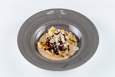 Fıstık ezmesi soslu karamelli ve ızgara muz, çikolata şurubu ve beyaz üzerine izole edilmiş fındık.