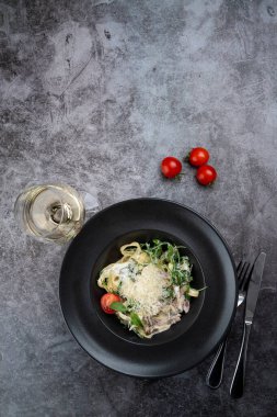 Tirol usulü jambonlu makarna ve bir bardak beyaz şarap, dikey fotokopi alanı.