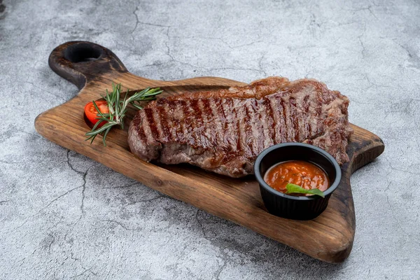 Strip beef steak with a glass of door red wine and ingredients on a stone table