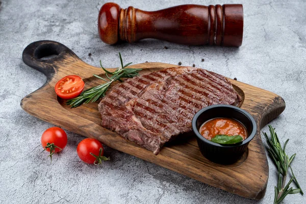 Strip beef steak with a glass of door red wine and ingredients on a stone table