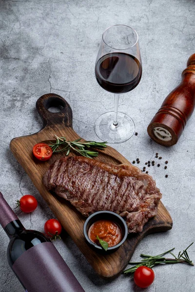 Biftek ve bir bardak kapı kırmızı şarap ve malzemeler taş bir masanın üzerinde.