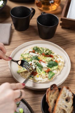 Genç bir kadın vejetaryen dolgulu bir ekmek yiyor: Çin lahanası, lahanası ve domates.
