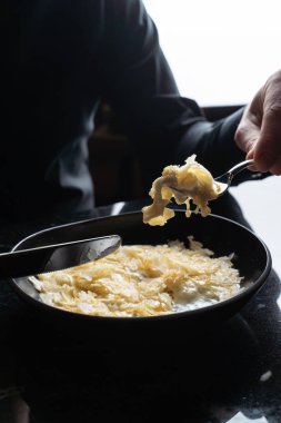 Adam çatal ve bıçakla muhallebi yiyor.