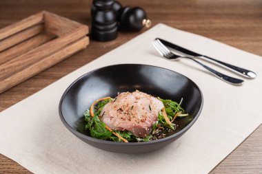 Siyah tabakta, deniz ürünleri restoranında marullu beyaz balık filetosu.