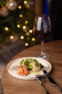 Şık bir restoranın masasında akşam vakti taze Çin lahanalı somon tartar ve bulanık ışıklar.