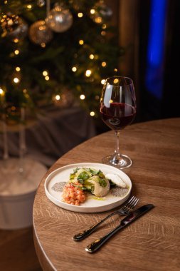 Şık bir restoranın masasında akşam vakti taze Çin lahanalı somon tartar ve bulanık ışıklar.