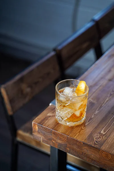 Classic old fashioned cocktail with bourbon and whiskey on wooden table in a neon light bar