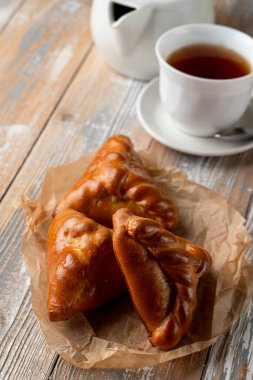 Geleneksel Rus köfteleri altın kabuklu, ahşap masada bir fincan çayla servis ediliyor.