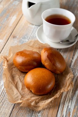 Geleneksel Rus usulü doldurulmuş pierogi altın kabuklu, ahşap masada bir fincan çayla servis edilir.