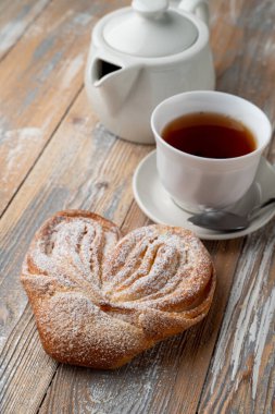 Geleneksel Rus Moskova usulü pudra şekerli çörekler, ahşap zemin üzerinde şekerli hamur tatlısı ve bir fincan çay.