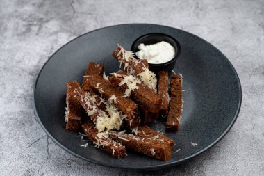 Gri mermer arka planda rendelenmiş parmesan peyniri ve sarımsak soslu kızarmış çavdar ekmeği.