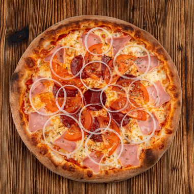 Soğanlı mini pizza, jambon ve salamlı, erimiş peynirli siyah ahşap masa.