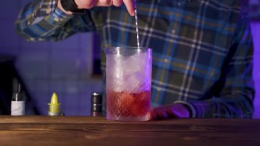 Barmen cam sürahide buz karıştırıyor, kokteyl yapıyor, yakınlaştırıyor.