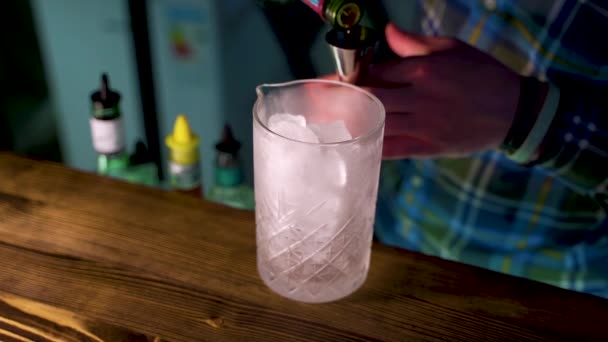 Barman mierzy whisky jiggerem i wlewa ją do koktajlu, ręce widoczne — Wideo stockowe