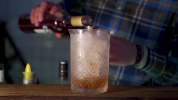 Bartender measures liqueur with jigger and adds it into cocktail, close up — Stock Video